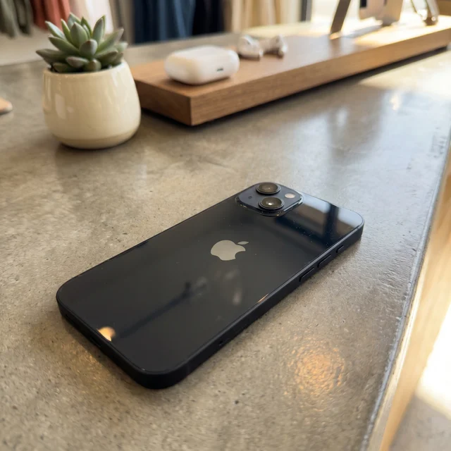 Lifestyle image of a person holding the refurbished iPhone 13 in Black, showcasing its slim design and everyday usability. From mendmyi.