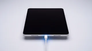 A single iPad propped upright on a clean studio surface with its screen dark and asleep