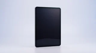 A single iPad propped upright on a clean studio surface with its screen dark and asleep