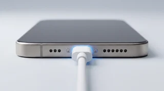 A single iPhone lying flat on a clean studio surface beside two contrasting USB-C cables, one neat and premium, one visibly cheap and frayed
