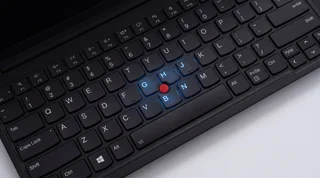 A single black Lenovo ThinkPad laptop open on a clean studio surface, showing its keyboard