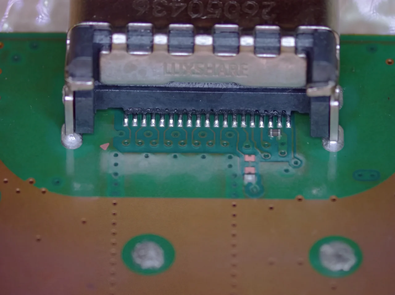 Macro photo of an actual PlayStation 5 HDMI port connector still mounted on the logic board during a real mendmyi repair, showing the row of internal pins