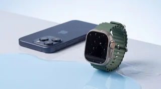 A refurbished iPhone, Google Pixel and Apple Watch lined up on the wet edge of a pool with water droplets on their screens