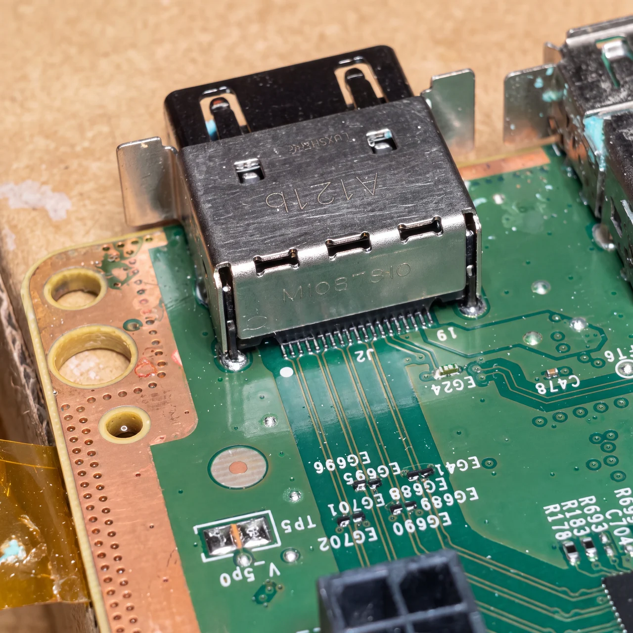 Macro photo of an actual Xbox HDMI port connector desoldered from the board during a real mendmyi repair, showing the row of internal pins on the green PCB