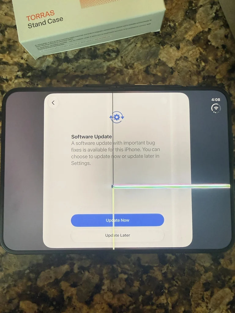 An iPhone Duo lying open on a granite worktop showing a software update prompt, a vertical line down the fold and a coloured horizontal line across the right half of the screen