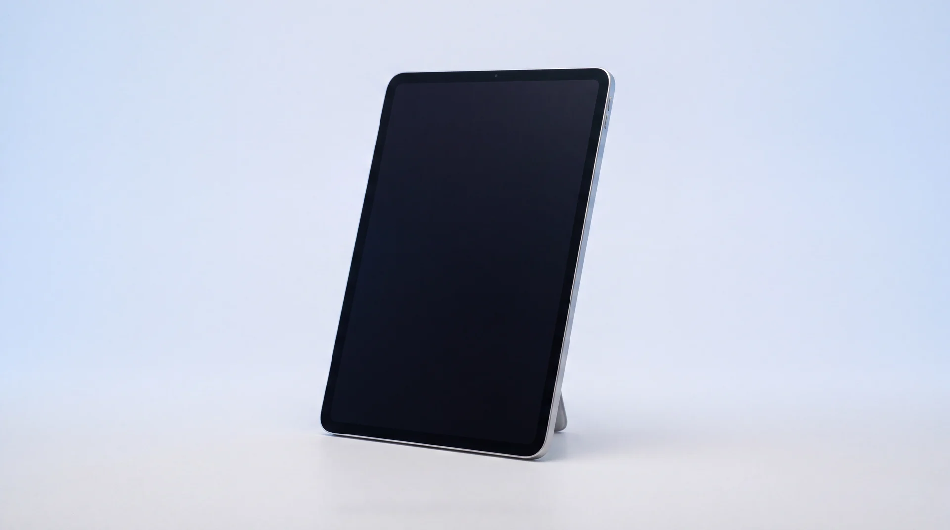 A single iPad propped upright on a clean studio surface with its screen dark and asleep
