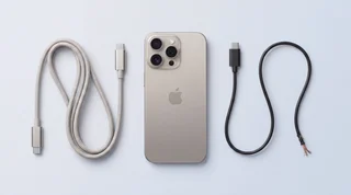 A single iPhone lying flat on a clean studio surface beside two contrasting USB-C cables, one neat and premium, one visibly cheap and frayed