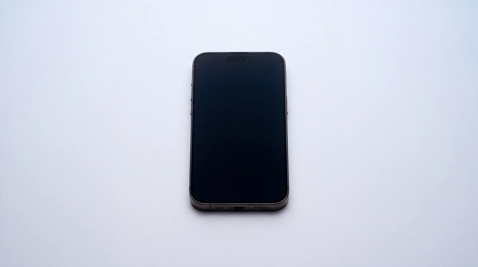 A single iPhone lying on a clean studio surface with its screen dark and asleep