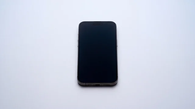 A single iPhone lying on a clean studio surface with its screen dark and asleep