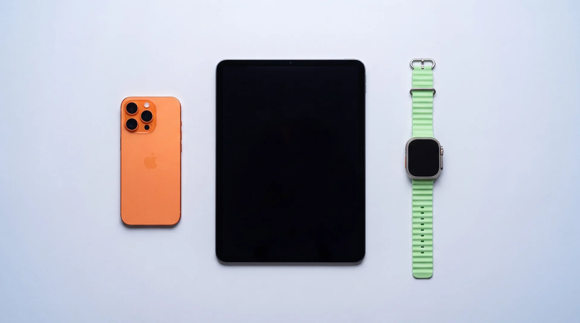 A refurbished iPhone, iPad and Apple Watch arranged neatly on a clean studio surface