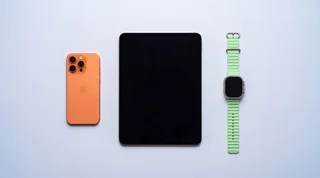 A refurbished iPhone, iPad and Apple Watch arranged neatly on a clean studio surface