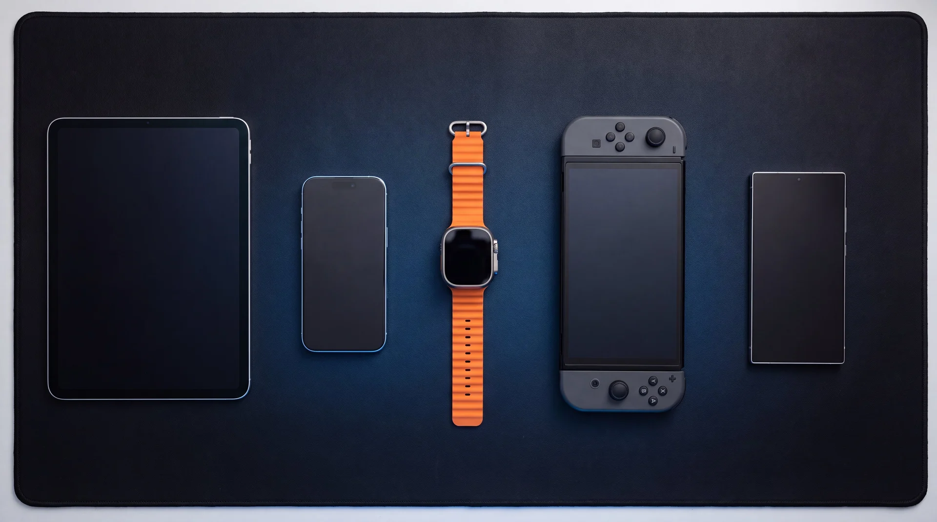 A line-up of phones, a tablet, a smartwatch and a handheld console laid out on the mendmyi workbench